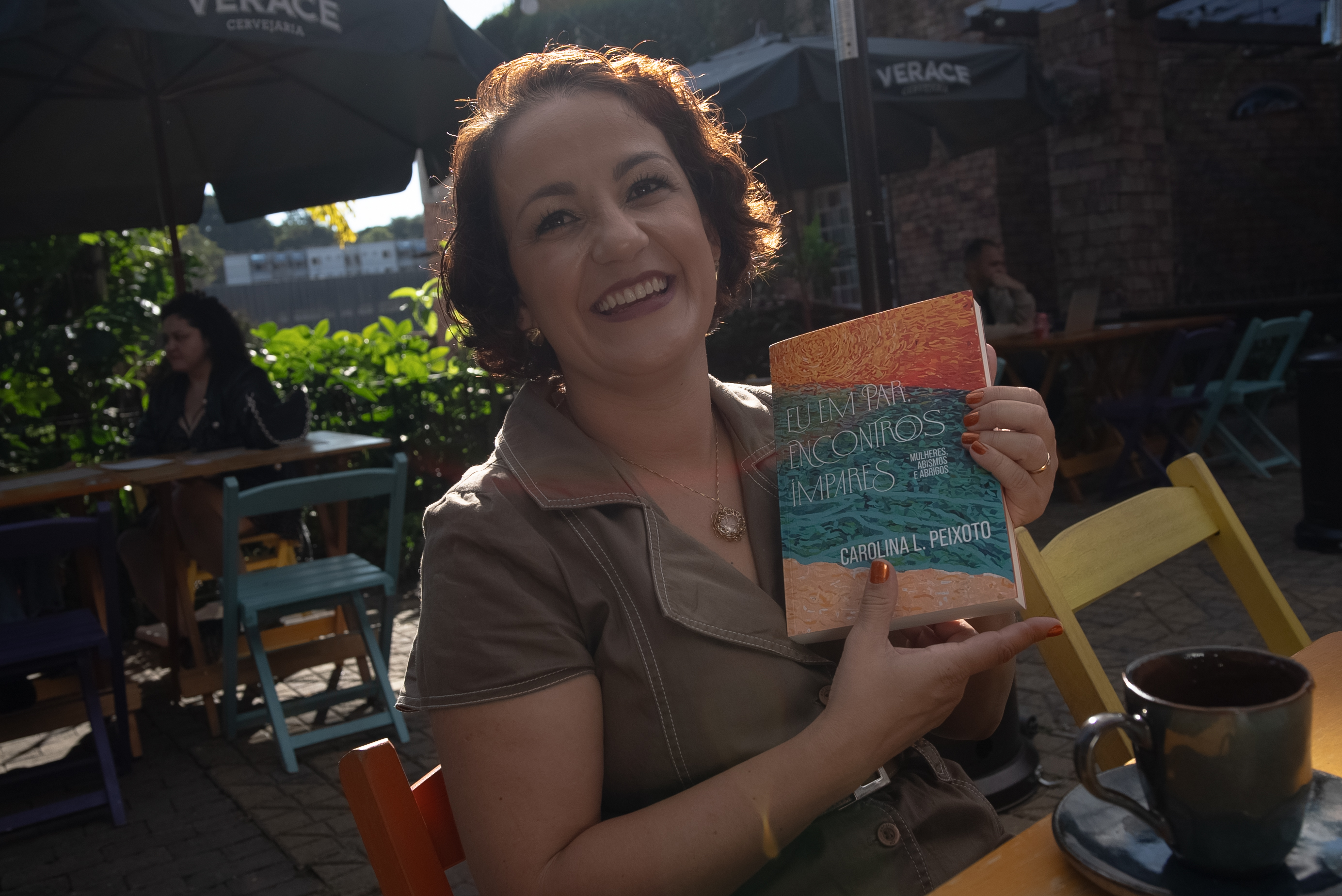 Carol Peixoto sorrindo e segurando o seu livro Eu em Par, Encontros Ímpares